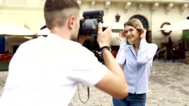 Turist çift. Kamera çekim kadının sokakta olan adam. Gülümseyen genç Çift seyahat ve fotoğrafları açık havada yapma şık giysiler içinde aşık. İnsanlar seyahat hafta sonu. Yüksek çözünürlük.