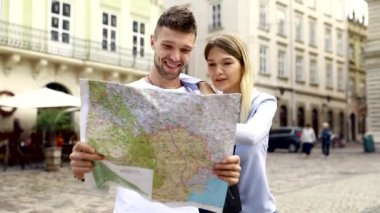 Harita ile bir gezi seyahat tatile kaç. Mutlu turist erkek ve kadın şık giysileri ile harita sokakları etrafında yürüyüş hafta sonu, seyahat. Turizm kavramı. Yüksek kaliteli görüntü.