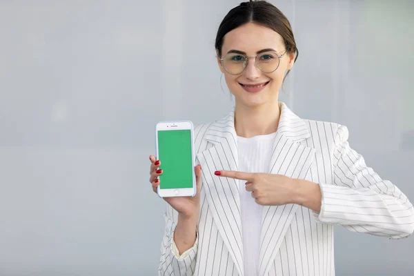 Усміхнена Молода Бізнес Леді Білому Піджаку Показує Смартфон Зеленим Екраном — стокове фото