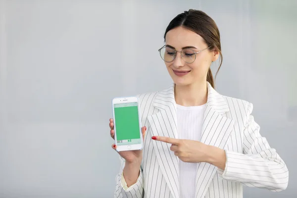 Усміхнена Молода Бізнес Леді Білому Піджаку Показує Смартфон Зеленим Екраном — стокове фото