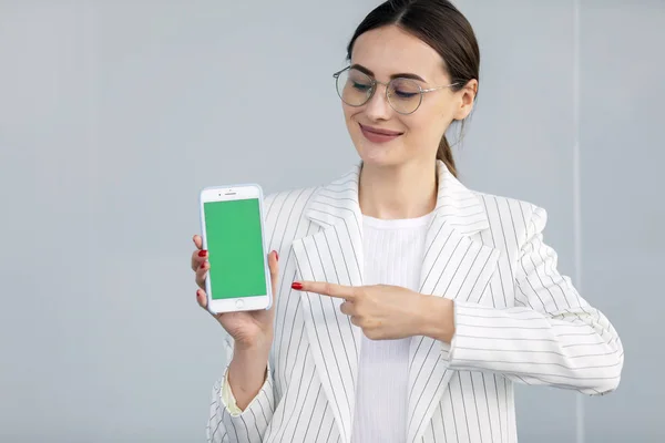 Lachende Jonge Zakelijke Vrouw Witte Jas Toont Smartphone Met Groen — Stockfoto