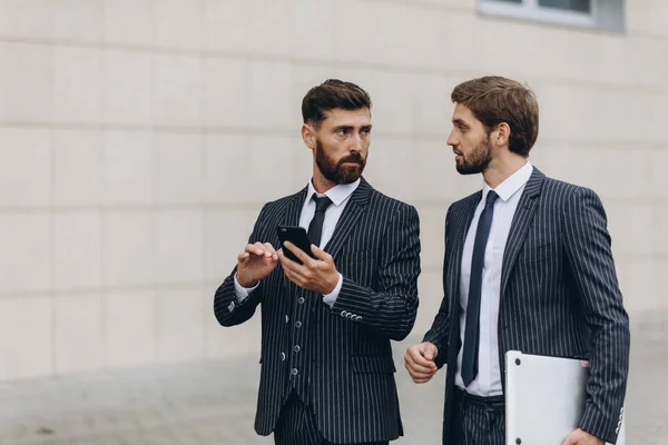 Two businessmen discussing together on a news on a smart phone during a business travel. Business, technology and people concept