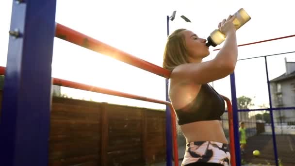 运动员妇女喝水从瓶子慢动作在健身房 口渴的白种女性在健身房进行艰苦的锻炼后 喝了两口瓶装水 从下面拍摄 — 图库视频影像