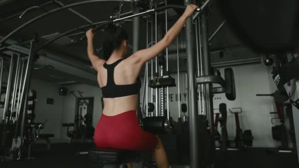 Aktiv tjejträning över rygg och armar på träningsmaskin — Stockvideo