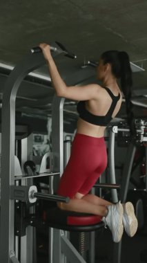 Spor salonundaki spor salonunda siyah taytlı atletik bir kadın yatay çubuğa yanaşıyor. İnsan kavramı, spor ve sağlıklı yaşam tarzı.