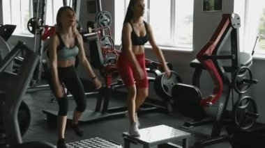 Ağır halterle çömelme hareketleri sırasında kadın müşterisini kontrol eden sağlıklı spor koçu. Güzel bir kadın spor salonunda profesyonel antrenörle çalışıyor..