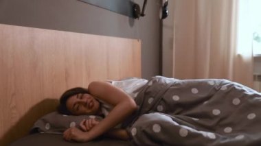 Beyaz gömlekli güzel esmer kadın temiz yumuşak çarşafların üzerinde uyuyor. Yorgun bayan dinlenme sırasında tatlı rüyalar görüyor. İyi geceler konsept.