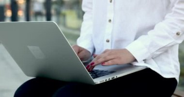 Sokakta dizüstü bilgisayarda iş yazışmaları yapan bir kadın.