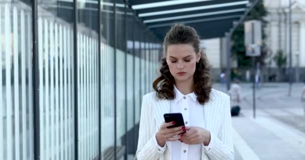 Mulher séria digitando mensagens no smartphone na rua — Vídeo de Stock