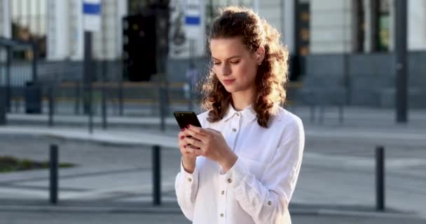 Γοητευτική κυρία χρησιμοποιώντας smartphone για κοινωνικά δίκτυα σε εξωτερικούς χώρους — Αρχείο Βίντεο
