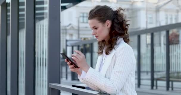 Charming lady browsing internet on smartphone outdoors — Stock Video