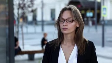 Ciddi yüz ifadesi olan çekici bir bayan girişimci iş merkezinde çalışmak için yola çıktı. Gözlüklü ve resmi kıyafetli genç bayan sokakta yürürken akıllı telefon ekranına bakıyor..