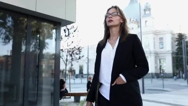 Mulher de negócios bonita em roupas de escritório elegantes andando na rua e usando smartphone moderno. Conceito de pessoas, tecnologia e carreira de sucesso . — Vídeo de Stock