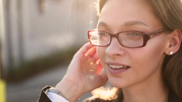 在室外风的吹拂下，穿着办公室衣服和眼镜的快乐女人正在整理她的棕色头发。成功的女人在镜头前表达真实的人类情感. — 图库视频影像