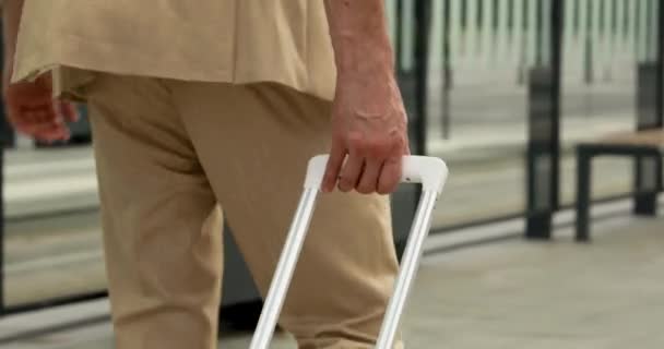 Close-up van mannelijke reiziger in business suit lopen op het station met witte koffer. Succesvolle man met zakenreis en werkbijeenkomst in een andere stad. — Stockvideo