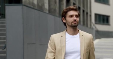 Resmi kıyafetli neşeli sakallı adamın portresi iş toplantısına gidiyor. Genç işadamı yapının yanında tek başına yürüyor ve gülümsüyor.