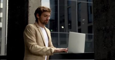 Ofis dışında kablosuz bilgisayarla çalışan resmi giysili yakışıklı bir genç. İşadamı dışarıda çalışmak için taşınabilir bilgisayar kullanıyor..