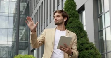 Ofis merkezinin yakınında dijital tablet kullanan resmi giyinmiş kendine güvenen sakallı bir iş adamı. İşten çıkarken temiz hava alan yakışıklı bir adam..