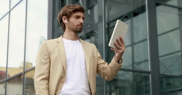 Hombre barbudo serio en traje de negocios que tiene reunión de trabajo con socios a través de videollamada en tableta digital. Concepto de conversación en línea y tecnología. — Vídeos de Stock