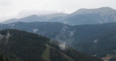 Yeşil orman ve yağmurlu havalarda gökyüzünde bulutlar olan dağların güzel manzarası. Doğal arkaplan ve duvar kağıdı.