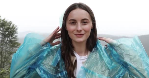 Bonita turista vestida con impermeable azul con capucha de senderismo en las montañas durante los días de lluvia. Concepto de naturaleza salvaje, aventura y relajación. — Vídeos de Stock