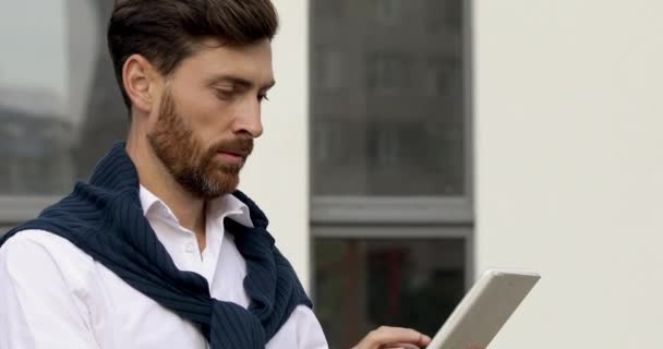 Retrato de hombre barbudo feliz en camisa blanca usando tableta digital para video chat cerca del centro de negocios. Ocupado macho líder reunión de trabajo en línea. — Vídeos de Stock