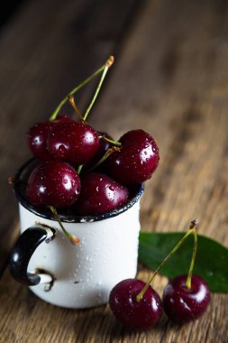Olgun kiraz ahşap arka plan üzerinde bir kupa