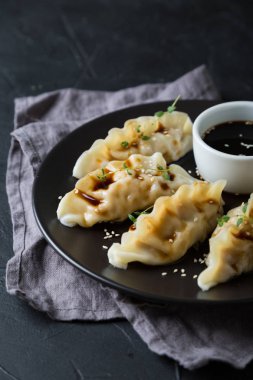 Koyu bir masada soya sosuyla doldurulmuş Wonton.