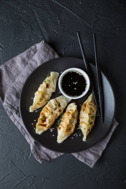 Koyu bir masada soya sosuyla doldurulmuş Wonton.