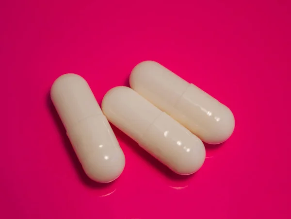 Close Van Drie Medische Capsules Een Geïsoleerde Roze Achtergrond — Stockfoto