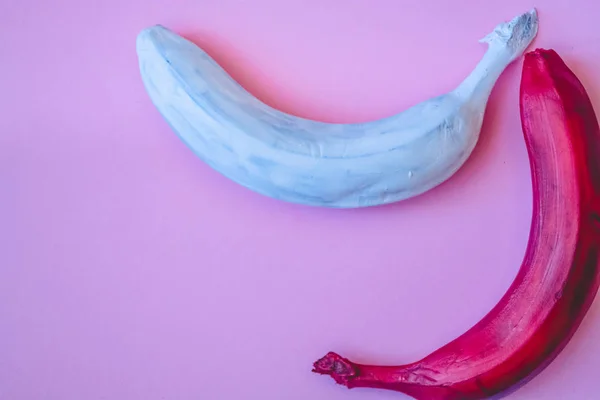 Multicolored bananas. A red banana. White banana. Pink background.