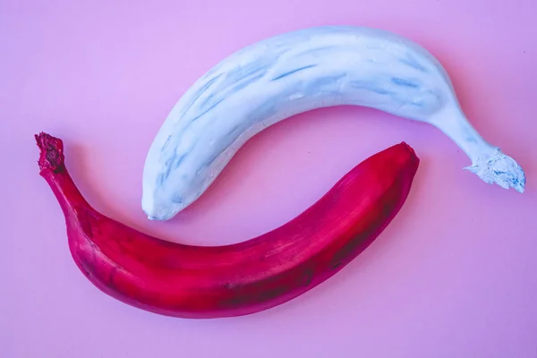 Multicolored bananas. A red banana. White banana. Pink background.