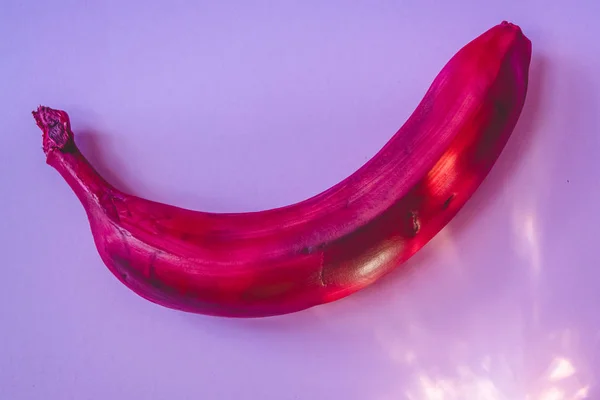 Multicolored bananas. A red banana. White banana. Pink background.