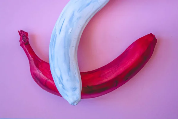 Multicolored bananas. A red banana. White banana. Pink background.