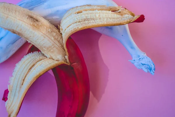 Multicolored bananas. A red banana. White banana. Pink background.