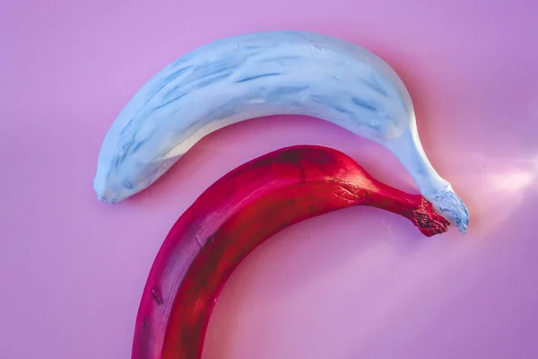 Multicolored bananas. A red banana. White banana. Pink background.