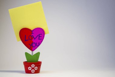 Beyaz arka plan. Ahşap kalp bir clothespeg için bir bahar üzerinde sopa ile. Kutlama. St. Valentine's Day. Sarı kağıt. 