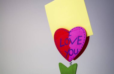 Beyaz arka plan. Ahşap kalp bir clothespeg için bir bahar üzerinde sopa ile. Kutlama. St. Valentine's Day. Sarı kağıt. 