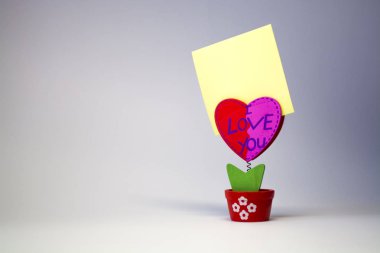 Beyaz arka plan. Ahşap kalp bir clothespeg için bir bahar üzerinde sopa ile. Kutlama. St. Valentine's Day. Sarı kağıt. 