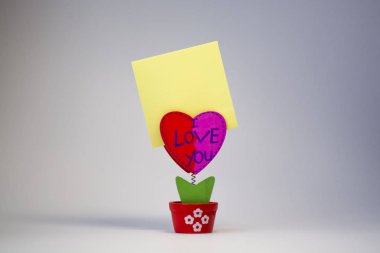 Beyaz arka plan. Ahşap kalp bir clothespeg için bir bahar üzerinde sopa ile. Kutlama. St. Valentine's Day. Sarı kağıt. 