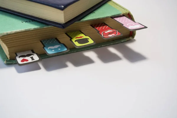 Pilha de livros antigos com as folhas amarelas viradas em um fundo branco. Marcadores alegres com bigodes de coloração diferente . — Fotografia de Stock