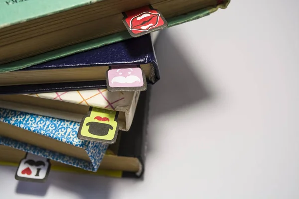 Pilha de livros antigos com as folhas amarelas viradas em um fundo branco. Marcadores alegres com bigodes de coloração diferente . — Fotografia de Stock