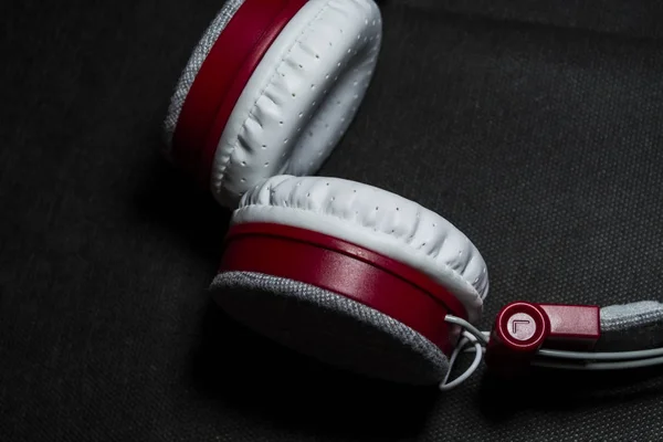 Auriculares grandes y blancos para escuchar música. Plástico rojo y piel. Sobre un fondo negro. Tecnologías modernas. Portabilidad . — Foto de Stock