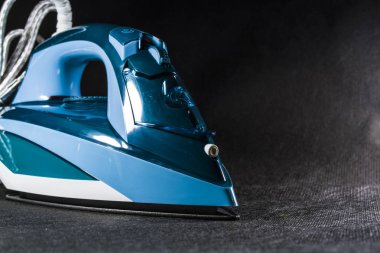 Mavi demir Ütü giysi. Tek sesli siyah arka plan. Ev aletleri. Her ülkede verilmektedir. Modern teknolojiler.