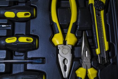 Büyük alet çantası siyah ve sarı renk bir kutu evi. Düz burun pense, vida sürücüleri, ileti örneği bıçak ve kerpetenler. 