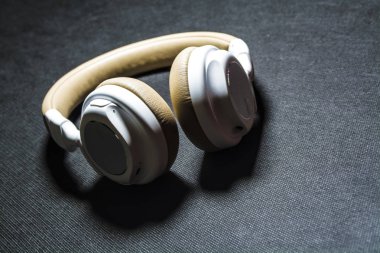 Siyah arka plan. Büyük müzik dinlemek için kulaklık. Beyaz ve bej renk. Cilt. Modern teknolojiler. Taşınabilir cihaz.