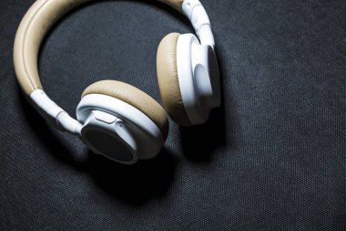 Siyah arka plan. Büyük müzik dinlemek için kulaklık. Beyaz ve bej renk. Cilt. Modern teknolojiler. Taşınabilir cihaz.