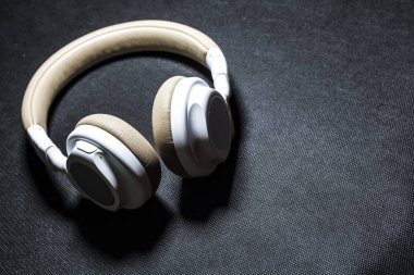 Siyah arka plan. Büyük müzik dinlemek için kulaklık. Beyaz ve bej renk. Cilt. Modern teknolojiler. Taşınabilir cihaz.