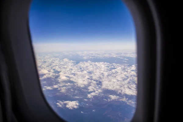 Blick aus einem Fenster des Passagierflugzeugs auf Himmel und Erde aus der Höhe. schöne Aussicht aus der Luft. Wolken und blauer Himmel. — Stockfoto