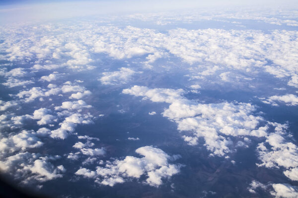 View from a plane window on clouds and blue clear sky and the earth from height. Beautiful view from air of mountains. 